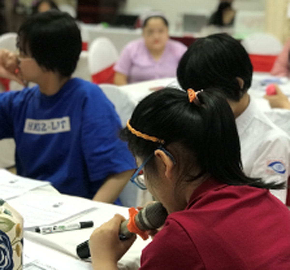 A group of people sitting around a table listening to one person speak into a microphone.