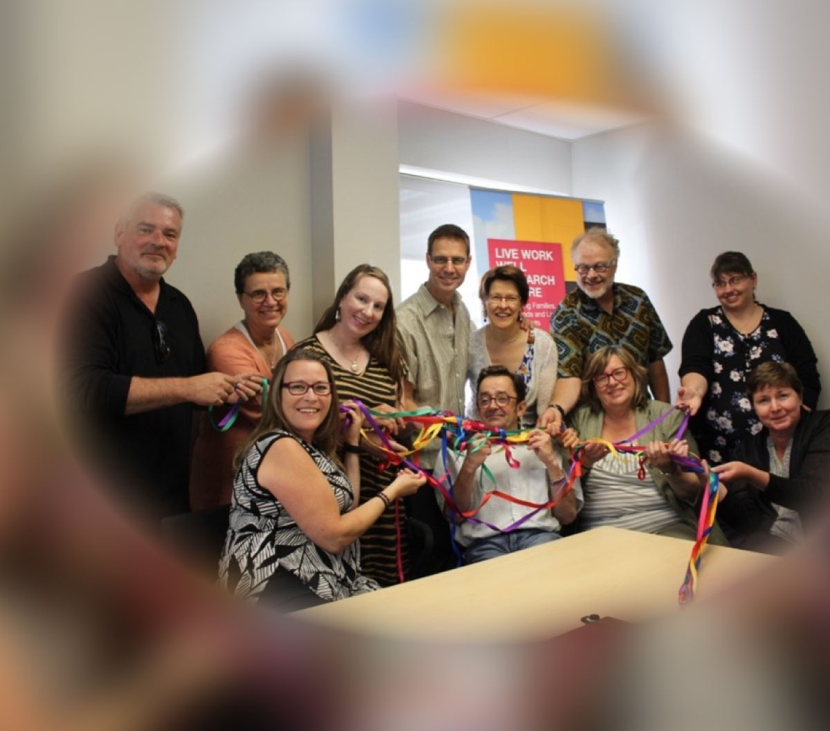 Texte alternatif : Un groupe comprenant des membres de l’équipe de direction et des partenaires du projet autour d’une table tenant un ruban tressé.