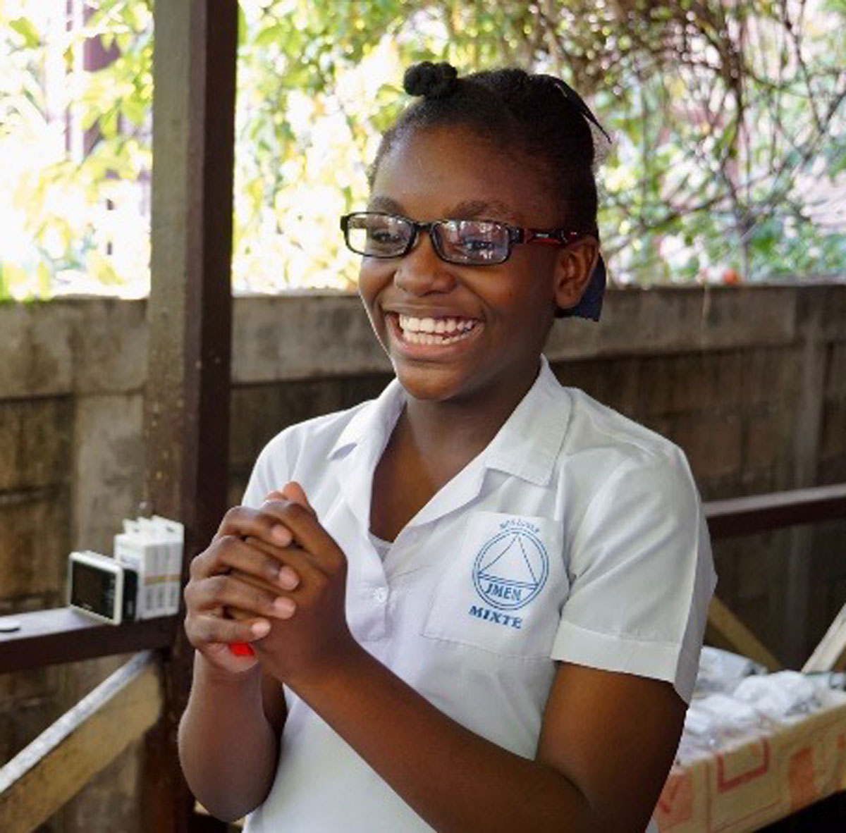 Texte alternatif : Jeune fille souriante portant une chemise blanche et des lunettes