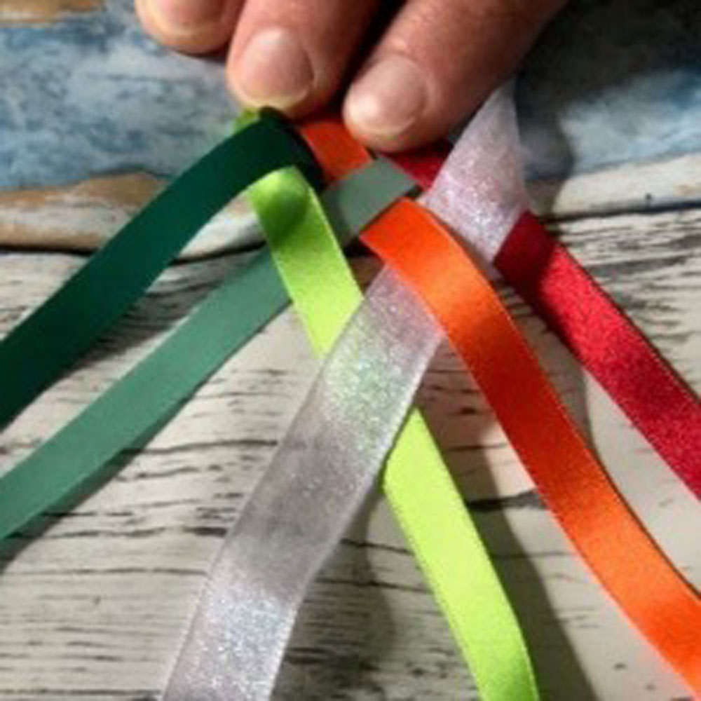 Texte alternatif : Six rubans de couleurs différentes tressés, posés à plat sur une table